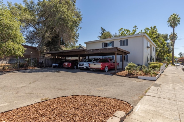 traditional home featuring covered parking, stucco siding, and fence