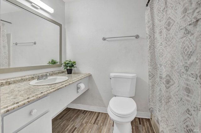 bathroom with baseboards, a shower with shower curtain, toilet, vanity, and wood finished floors