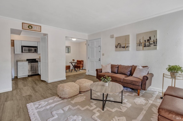 living room with ornamental molding, baseboards, and light wood-type flooring
