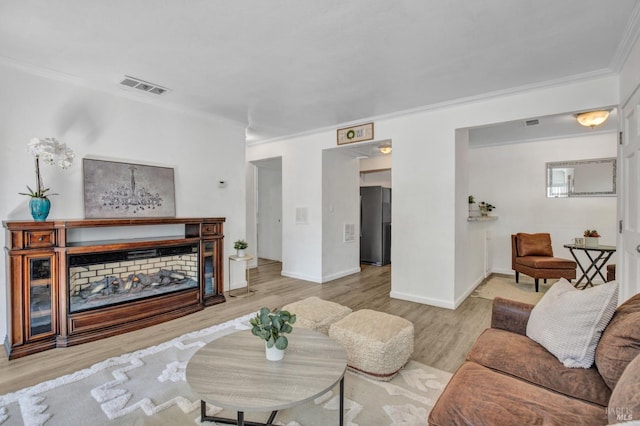 living area featuring visible vents, baseboards, crown molding, and wood finished floors