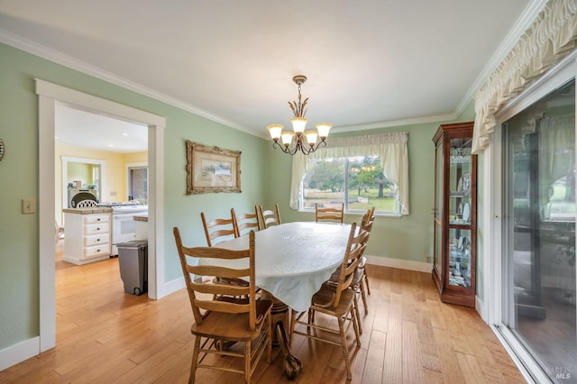 dining space with light wood-style flooring, crown molding, baseboards, and a chandelier