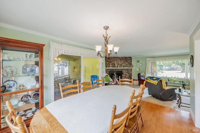 dining space featuring wood finished floors, an inviting chandelier, crown molding, and a brick fireplace
