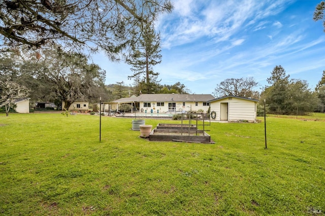 rear view of property featuring a lawn and a vegetable garden