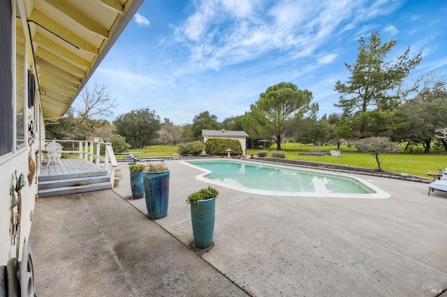 pool featuring a patio, a deck, and a lawn