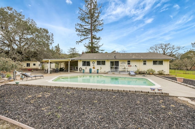 rear view of house featuring an outdoor pool and a patio area