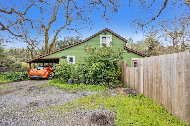 view of home's exterior featuring an attached carport and fence