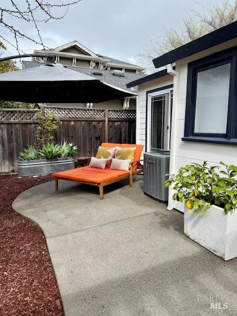 view of patio with cooling unit and fence