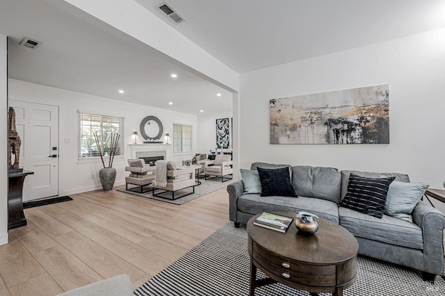 living room featuring visible vents, a fireplace, light wood-style flooring, and recessed lighting