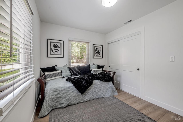 bedroom featuring a closet, baseboards, light wood-style floors, and visible vents