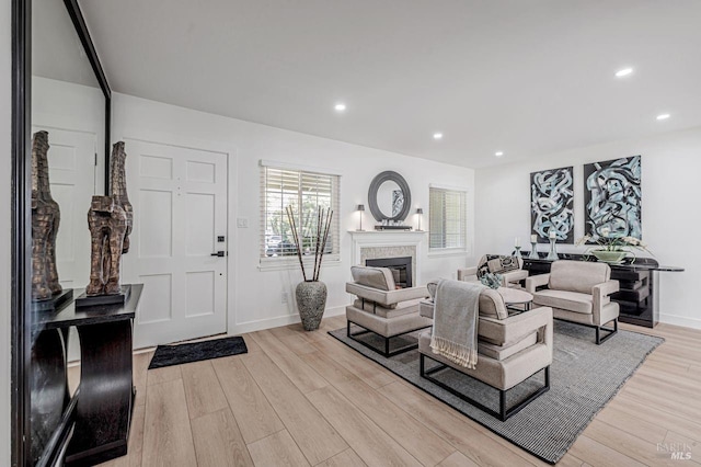 living room featuring baseboards, recessed lighting, a glass covered fireplace, and light wood-style floors