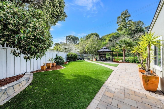 view of yard with a fenced backyard, a gazebo, and a patio area