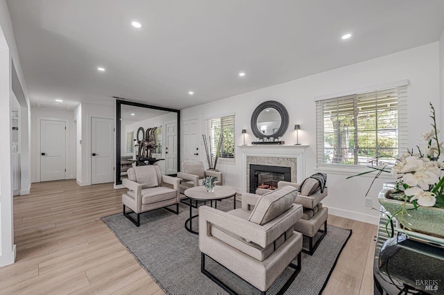 living room featuring light wood-type flooring, recessed lighting, and a glass covered fireplace
