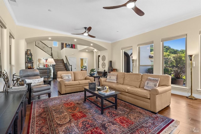living area featuring arched walkways, ceiling fan, and crown molding