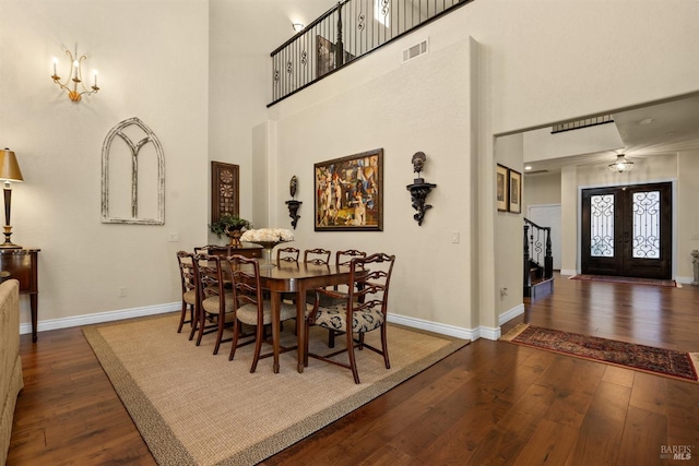 dining room featuring wood-type flooring, a high ceiling, visible vents, and baseboards