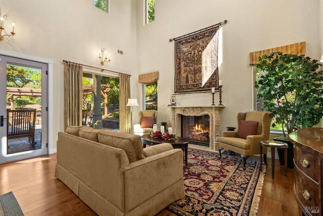living room with hardwood / wood-style flooring, plenty of natural light, a towering ceiling, and a premium fireplace
