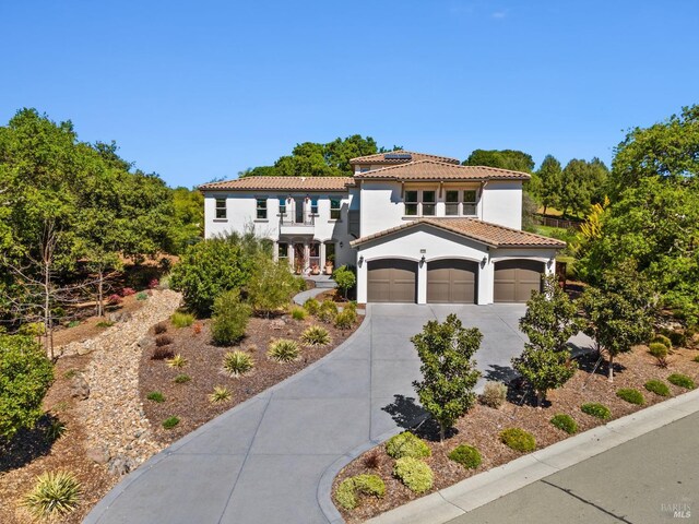 mediterranean / spanish house featuring a tiled roof, concrete driveway, an attached garage, a balcony, and stucco siding