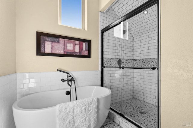 full bath with a freestanding bath, a shower stall, and tile walls