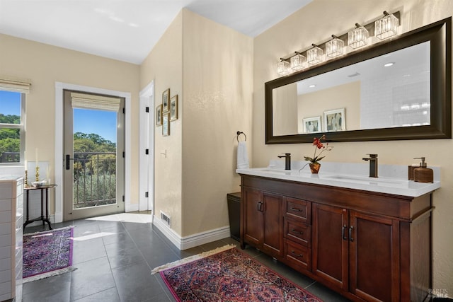 bathroom with baseboards, tile patterned floors, a sink, and double vanity