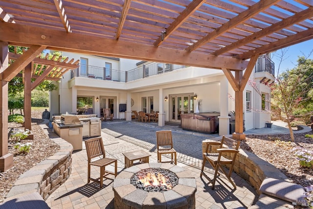 view of patio / terrace with french doors, a hot tub, a balcony, area for grilling, and an outdoor fire pit