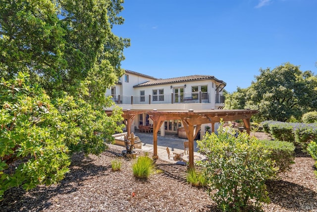 back of property with a tiled roof, stucco siding, a patio area, french doors, and a carport