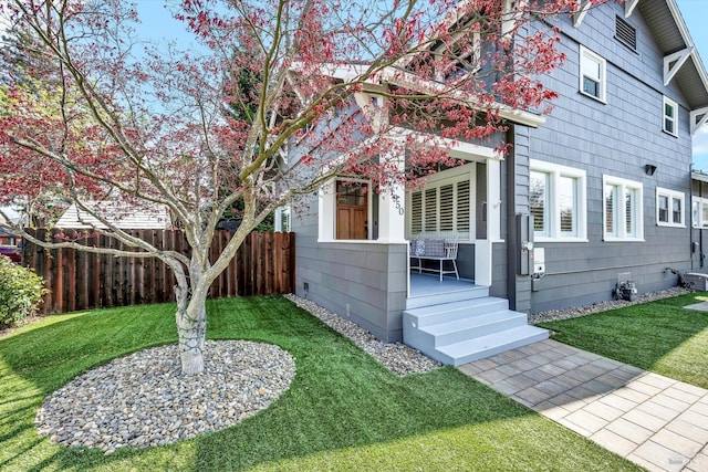 view of front of home featuring a front yard, a porch, and fence