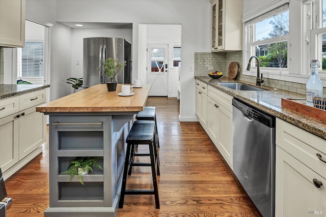 kitchen featuring glass insert cabinets, a sink, wooden counters, dark wood finished floors, and stainless steel appliances