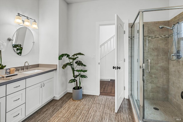 full bath featuring a stall shower, vanity, and wood finish floors