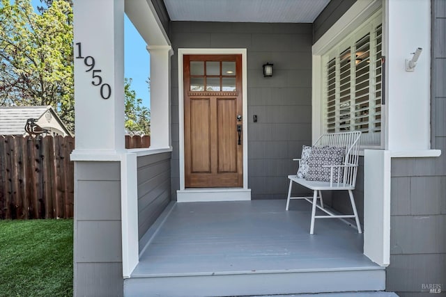 view of exterior entry with fence and covered porch