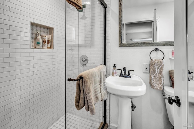 bathroom with a shower stall, a sink, and toilet