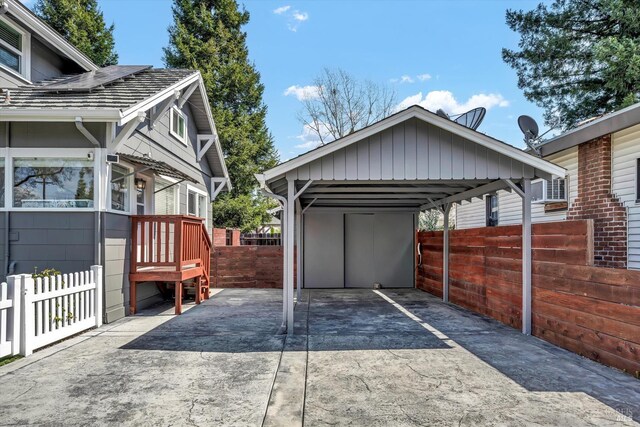view of vehicle parking with concrete driveway, a detached carport, and fence