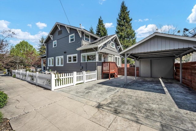 view of front of house with driveway, a detached carport, and a fenced front yard