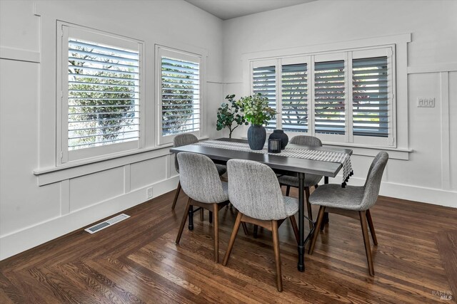 dining room featuring a decorative wall, visible vents, and dark wood-style floors