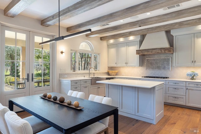 1149 Hudson Ave, Saint Helena, CA 94574 - kitchen with a center island, custom exhaust hood, french doors, light countertops, and black gas cooktop