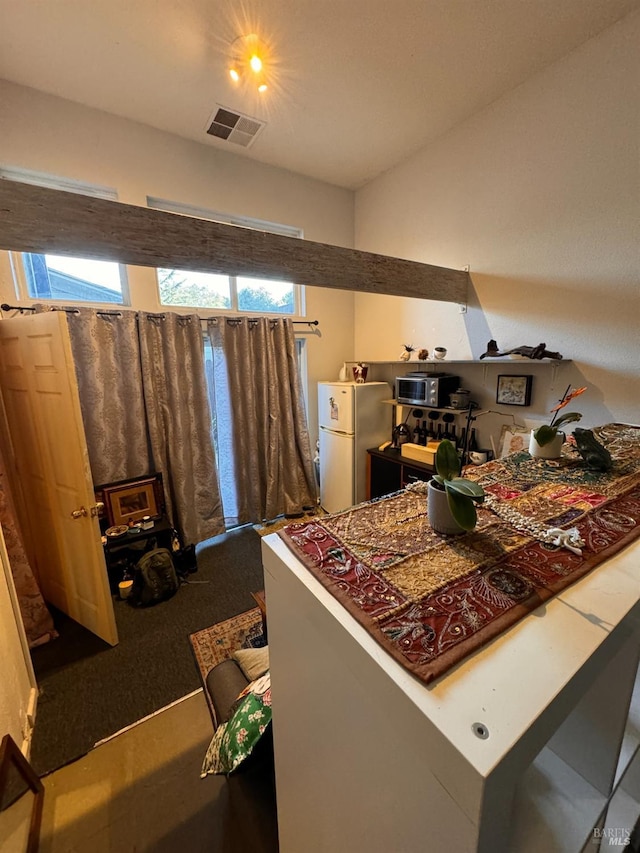 interior space featuring visible vents, carpet, and freestanding refrigerator