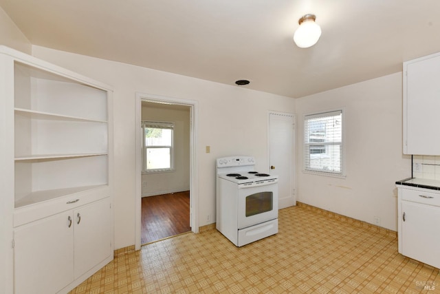 kitchen featuring white cabinetry, a healthy amount of sunlight, light floors, and electric range