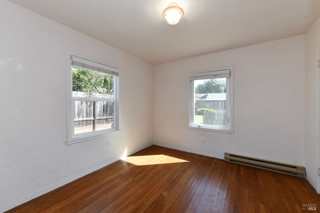 empty room with plenty of natural light, baseboard heating, and wood-type flooring
