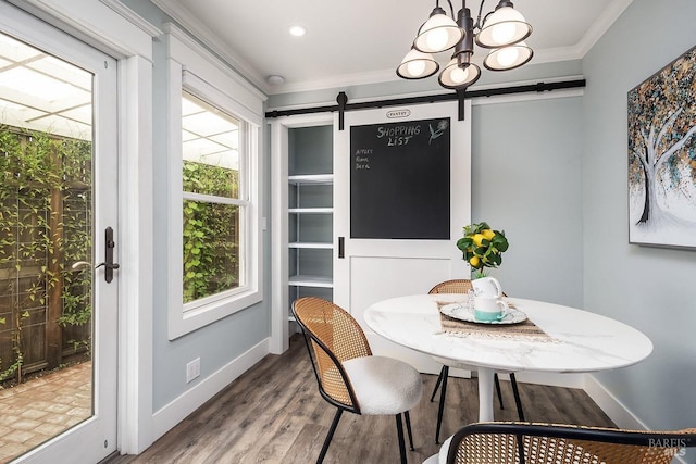 dining space featuring a chandelier, a barn door, ornamental molding, and wood finished floors