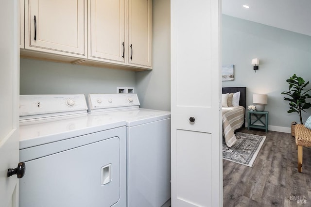 clothes washing area with baseboards, washer and clothes dryer, wood finished floors, and cabinet space