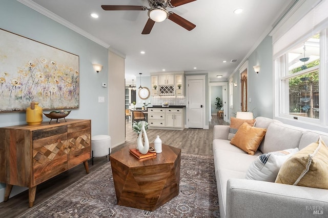 living room with dark wood-style flooring, ornamental molding, recessed lighting, and a ceiling fan