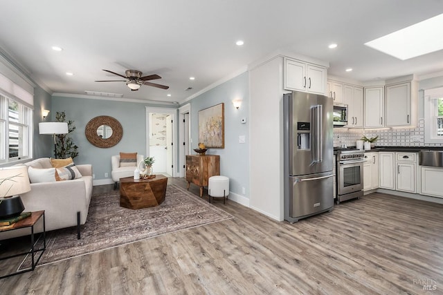 living area with crown molding, wood finished floors, baseboards, and plenty of natural light