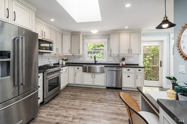 kitchen featuring dark countertops, tasteful backsplash, a sink, and high quality appliances