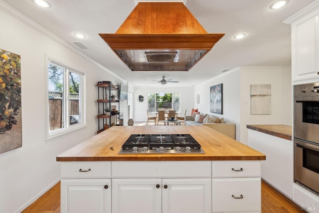 kitchen featuring crown molding, wood counters, appliances with stainless steel finishes, and custom exhaust hood