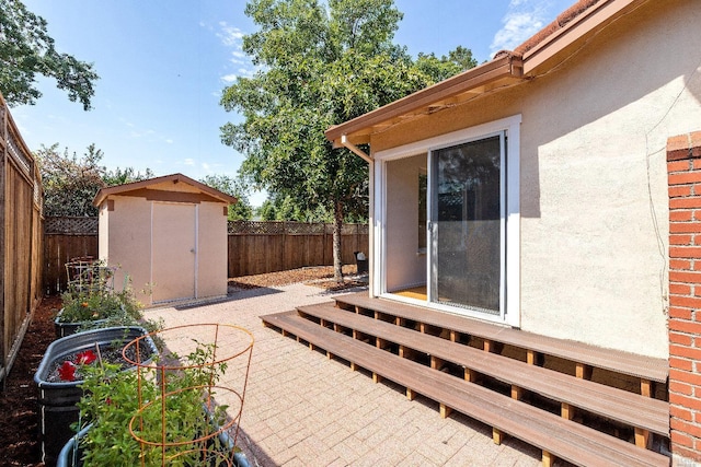 view of patio with entry steps, an outbuilding, a fenced backyard, and a storage shed