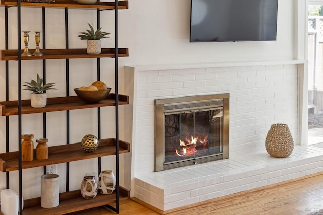 interior details with a brick fireplace and wood finished floors