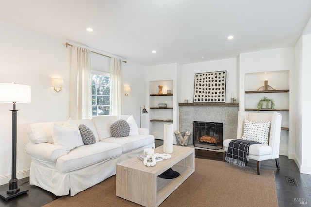 living room featuring recessed lighting, a tile fireplace, built in features, and wood finished floors