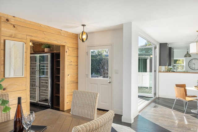 dining room with dark wood finished floors, baseboards, wood walls, and a healthy amount of sunlight