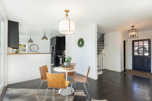 dining space featuring stairs, a notable chandelier, baseboards, and dark wood-type flooring