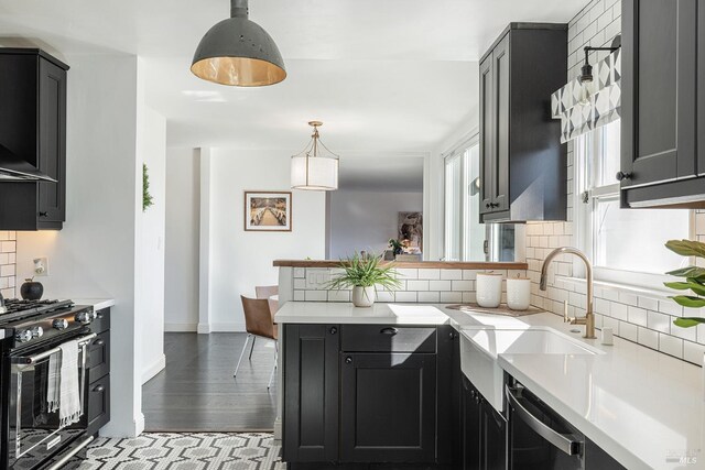kitchen with backsplash, light countertops, a sink, and black gas range