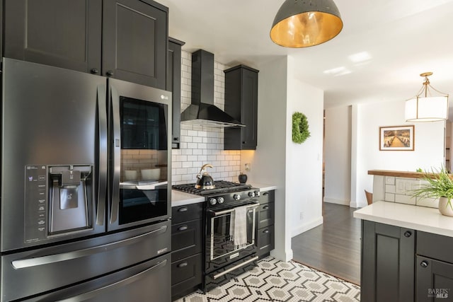 kitchen featuring light countertops, tasteful backsplash, stainless steel refrigerator with ice dispenser, gas stove, and wall chimney exhaust hood
