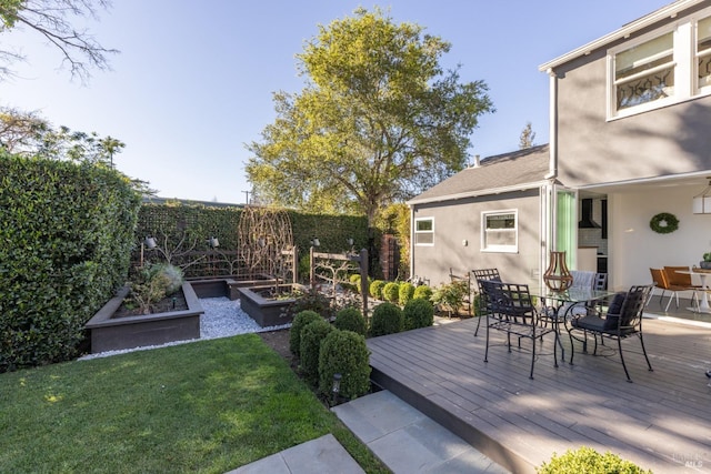 deck featuring outdoor dining space, a yard, fence, and a vegetable garden